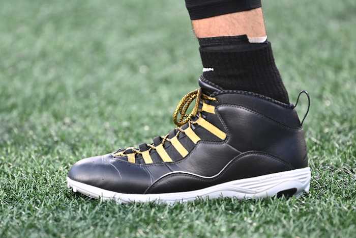 A detailed view of Derek Carr's black and gold Air Jordan cleats.